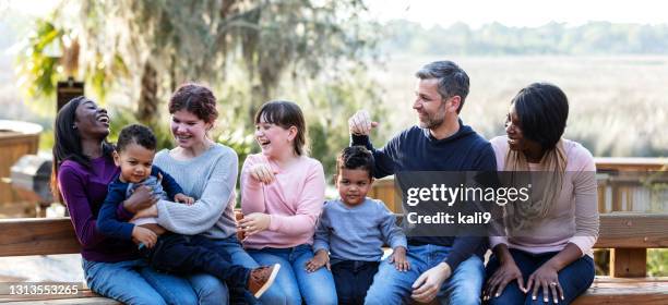 familia mezclada con cinco niños sentados en el banco del parque - adopción fotografías e imágenes de stock