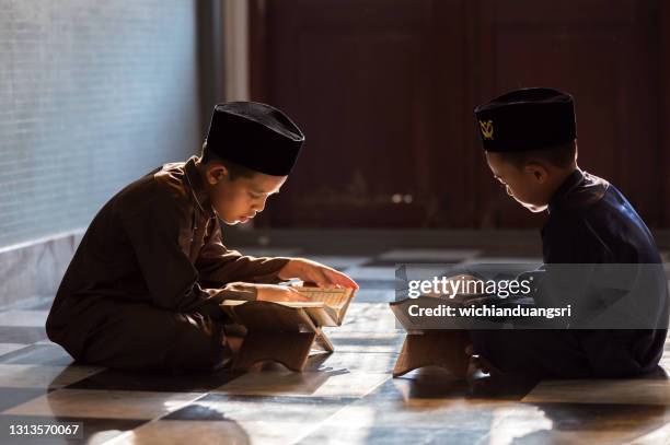 muslim boy reads the quran in mosque islamic concept - koran stock pictures, royalty-free photos & images