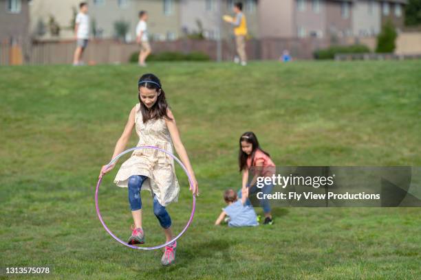 nettes mädchen spielt mit einem hula-reifen im park - kinder hula hoop reifen stock-fotos und bilder
