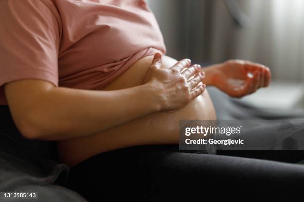 het toepassen van moisturizer op buik - belly rub stockfoto's en -beelden