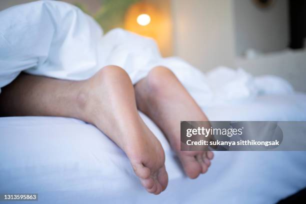 man's feet underneath a duvet in bed. - under value stock pictures, royalty-free photos & images