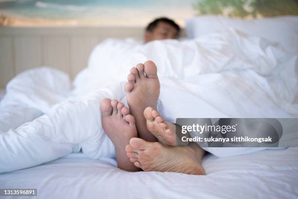 shot of couple's feet underneath a duvet in bed. - pareja abrazados cama fotografías e imágenes de stock