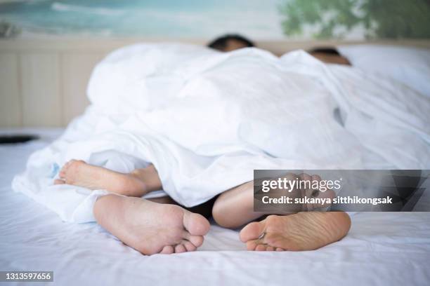 shot of feet a couple in bed under the blanket. - couple under sheets ストックフォトと画像