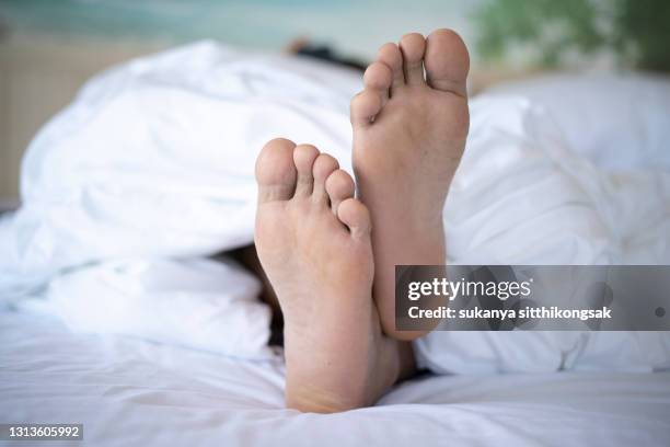 man's feet underneath a duvet in bed.(focus on feet) - male feet soles 個照片及圖片檔