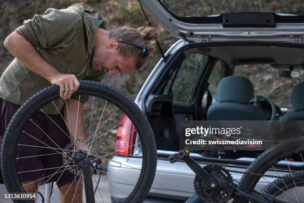 man taking his mountain bike out from the trunk of a car - hatchback stock pictures, royalty-free photos & images