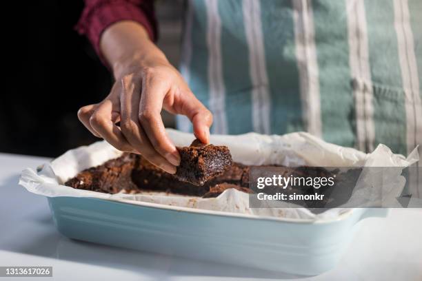 woman holding chocolate brownie in hand - papel de cera imagens e fotografias de stock