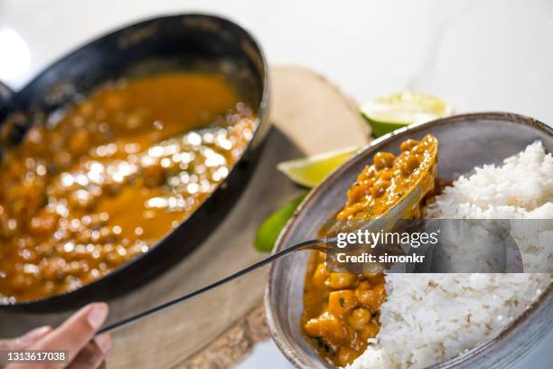 woman adding chickpea curry in rice bowl - indian curry stock pictures, royalty-free photos & images