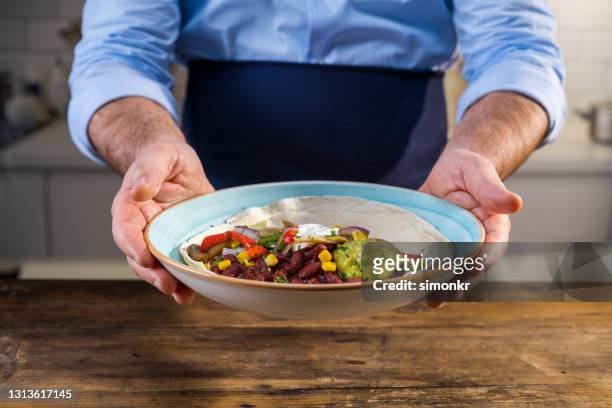 man holding tortilla served on plate - fruits table top imagens e fotografias de stock