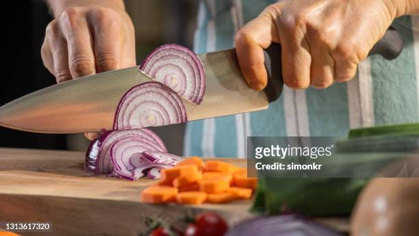 woman cutting onion on chopping board - cebola imagens e fotografias de stock