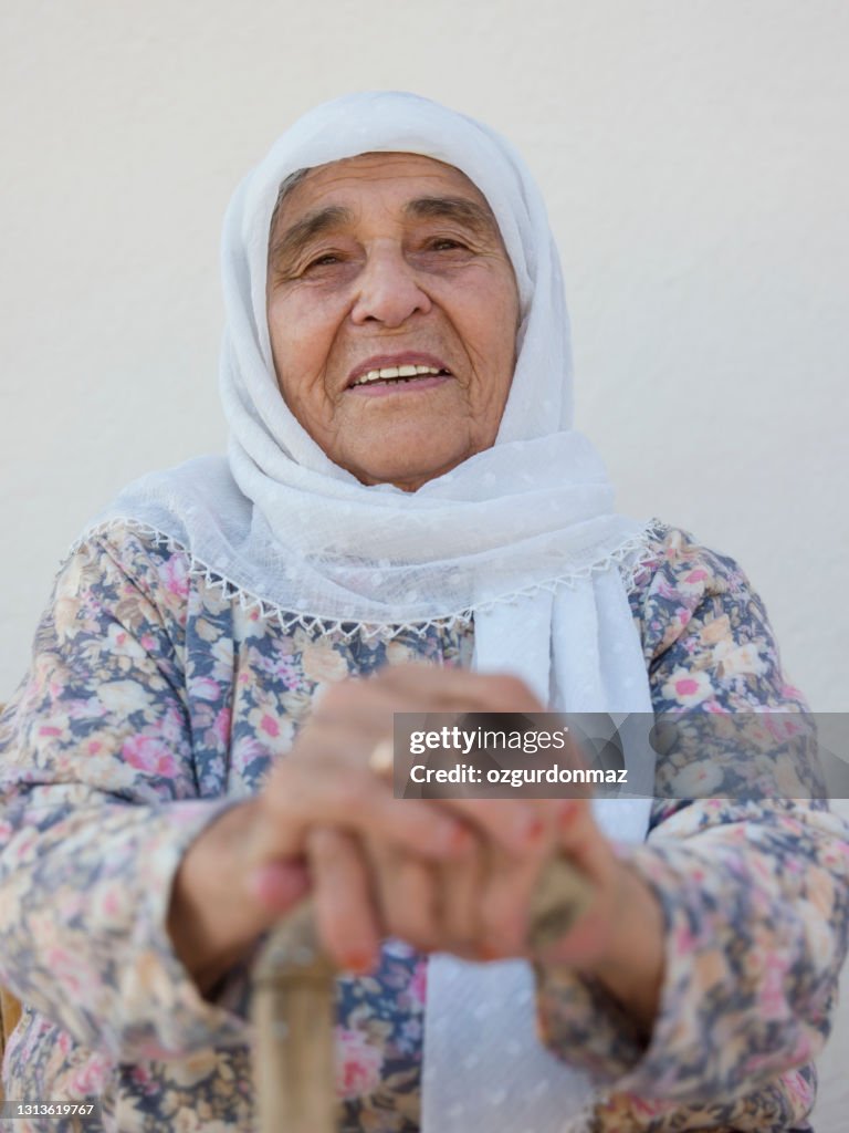 Outdoor portrait of an elderly woman sitting in front of her house, Mugla, Turkey
