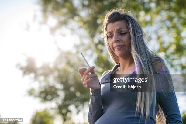 zwangere vrouwen whit sigaret op het park - rookkwestie stockfoto's en -beelden