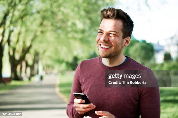 man with smart phone smiling - brunette smiling stock pictures, royalty-free photos & images