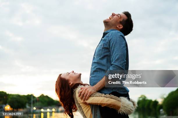 woman holding man in air - air date stockfoto's en -beelden