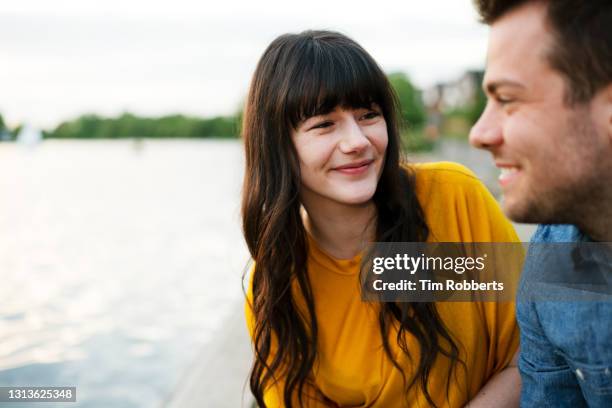 woman looking at man, next to water - candid couple stock pictures, royalty-free photos & images