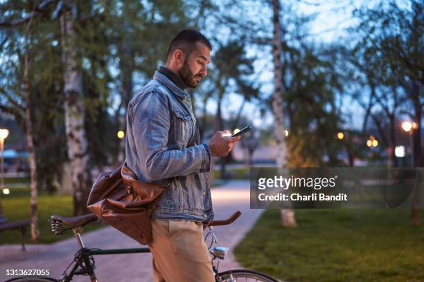 charming modern man, using online social app on his mobile phone, to meet the new people during his city break - content stock pictures, royalty-free photos & images