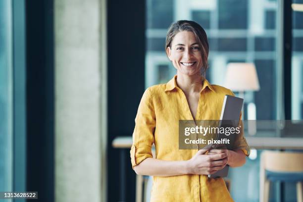 smiling businesswoman holding a laptop - holding laptop stock pictures, royalty-free photos & images