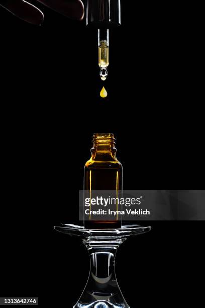 bottle of massage oil or facial serum for spa treatment on dark black background. - brown bottle stock pictures, royalty-free photos & images
