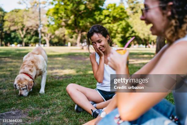 two women and dog relaxing in park - off leash dog park stock pictures, royalty-free photos & images