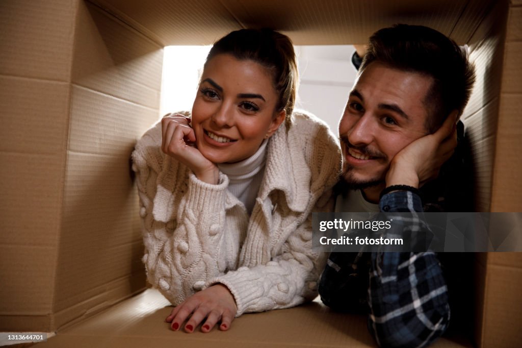 Coppia sdraiata all'interno di una scatola e contemplando la loro nuova vita insieme