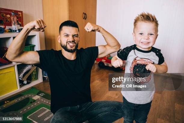 portrait of father and son flexing muscles - serrare i denti foto e immagini stock