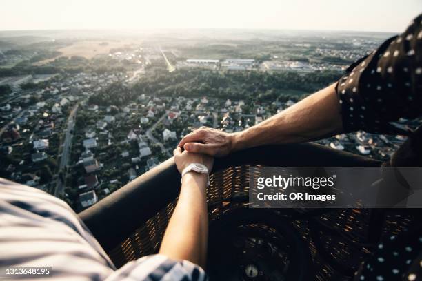 couple holding hands in a hot-air balloon - heißluftballon stock-fotos und bilder