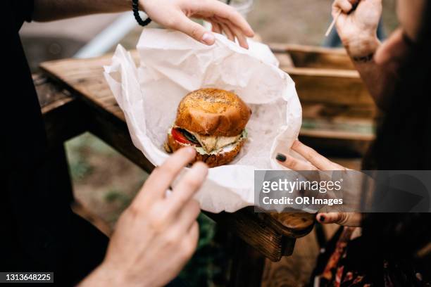 close-up of couple with a hamburger outdoors - unwrapping burger stock pictures, royalty-free photos & images