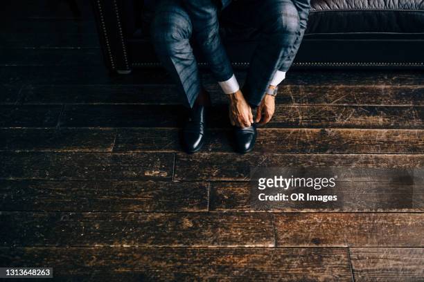 elegant businessman putting on shoes - shoes man foto e immagini stock