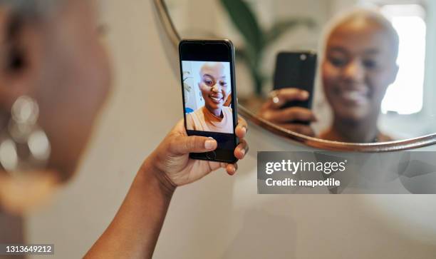 young african woman smiling and taking selfies in front of a mirror - mirror selfie stock pictures, royalty-free photos & images
