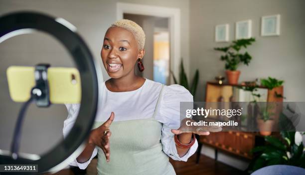 glimlachende jonge afrikaanse vrouwelijke influencer die een vlogpost thuis doet - black makeup stockfoto's en -beelden