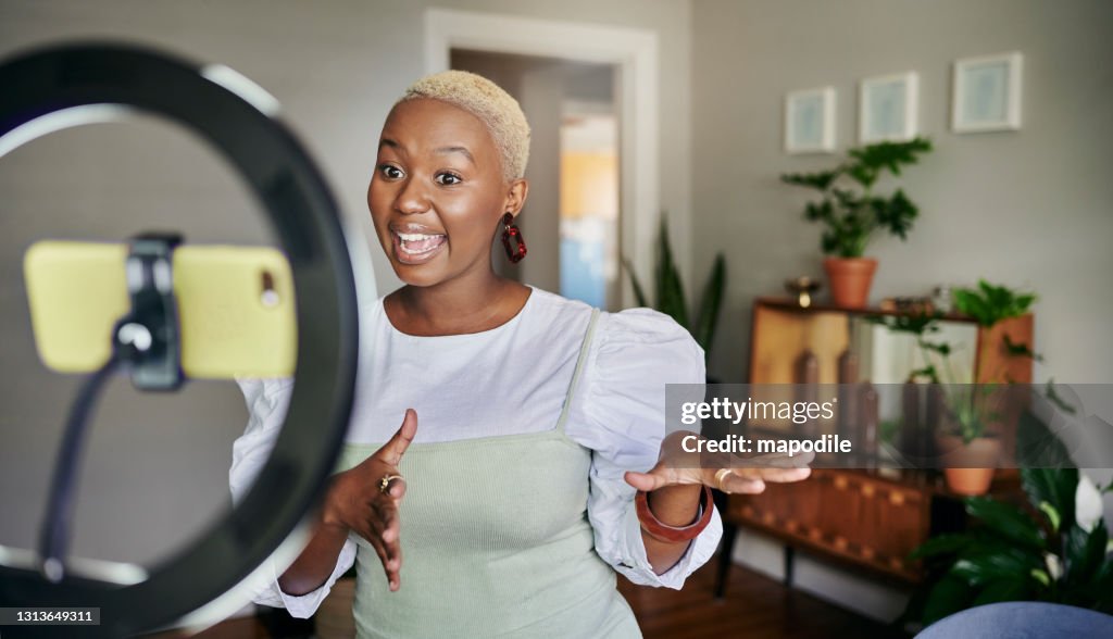 Smiling young African female influencer doing a vlog post at home
