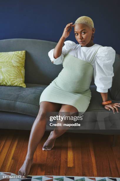 stylish young african woman sitting on a sofa at home - plus size fashion stock pictures, royalty-free photos & images