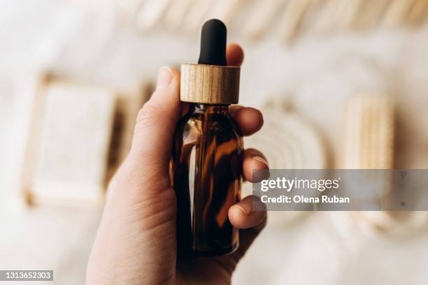 brown cosmetic jar with a pipette in woman hand - gesicht kosmetik maske stock-fotos und bilder