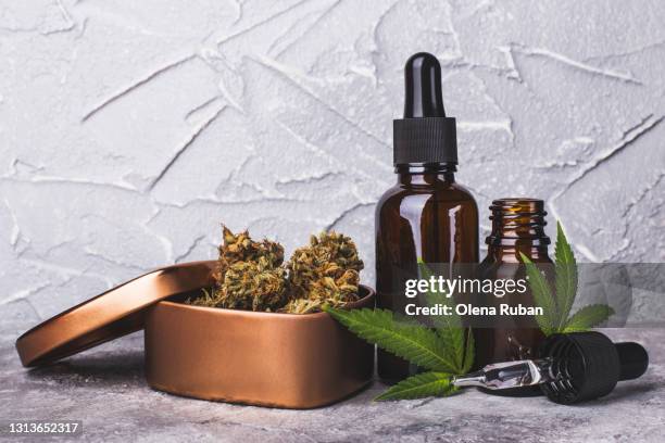 cannabis cbd oil extracts in jars near a slide of marijuana cones - cbd stock-fotos und bilder