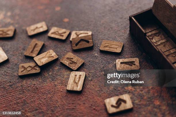 wooden runes with carved letters are scattered near a wooden box - wicca stock pictures, royalty-free photos & images