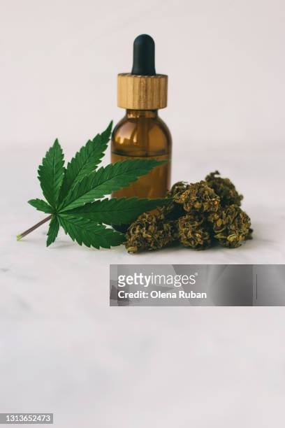 cannabis cbd oil extracts in jars near a slide of marijuana cones and leaf - cannabis oil - fotografias e filmes do acervo