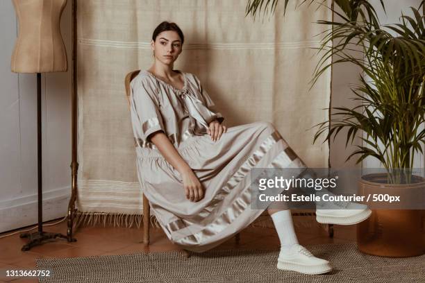 stylish and fashionable young woman in dress sitting with plant,avignon,france - art modeling studio stock-fotos und bilder