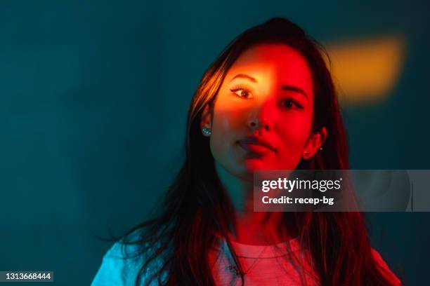 portrait of beautiful woman lit by neon colored lights - neon lighting smiling stock pictures, royalty-free photos & images