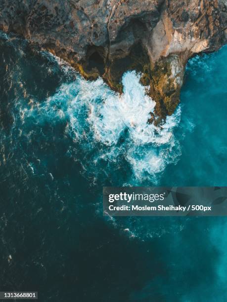 vertical aerial shot of sea waves hitting the cliff - cliff stock pictures, royalty-free photos & images
