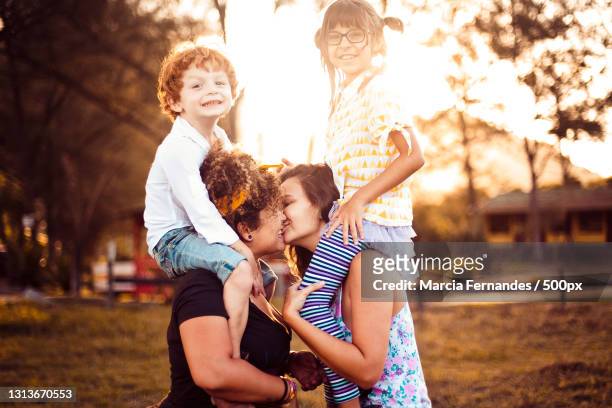 lesbian mothers kissing while giving son and daughter a piggy back ride,victoria,british columbia,canada - images of lesbians kissing stock pictures, royalty-free photos & images