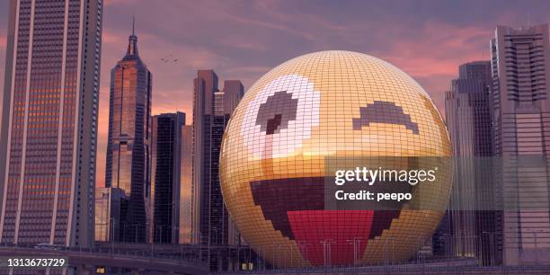 bâtiment en forme d’emoji souriant clignant des yeux avec la langue dehors au milieu des gratte-ciel de ville du centre-ville - funny avatar photos et images de collection