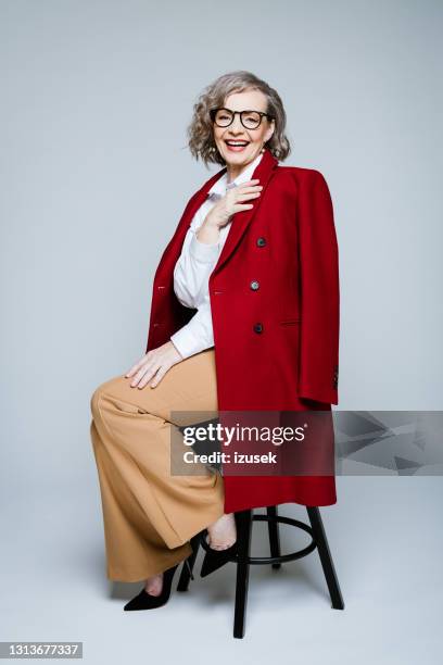 fashion portrait of stylish senior woman wearing red coat - red spectacles stock pictures, royalty-free photos & images
