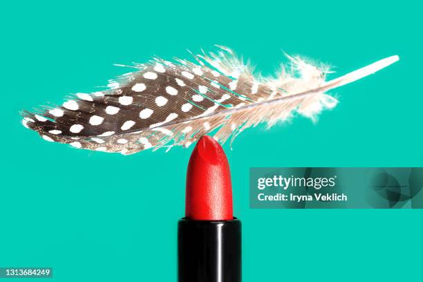 red lipstick and  light gentle feather on mint green background. - damp lips stock-fotos und bilder