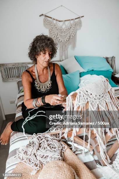 senior woman weaving with white string in home,san bartolo,peru - macrame stock-fotos und bilder