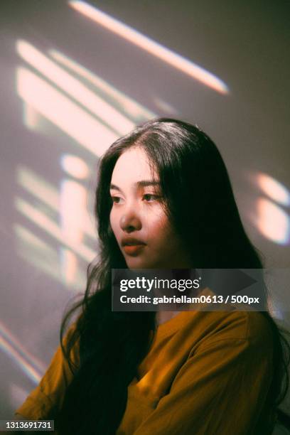 young woman looking away against wall - editorial woman stock pictures, royalty-free photos & images