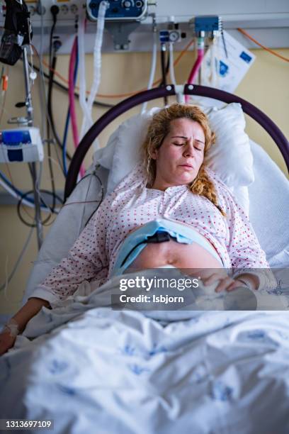mother labours in hospital bed during childbirth. - delivery room stock pictures, royalty-free photos & images