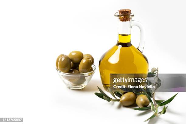 fresh extra virgin olive oil in a bottle, green olives and olive tree branches - olive oil ストックフォトと画像
