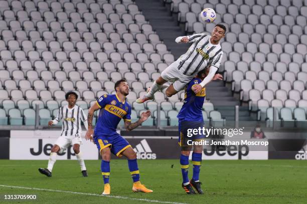 Giuseppe Pezzella of Parma Calcio looks on as Cristiano Ronaldo of Juventus leaps above Mattia Bani of Parma Calcio for an aerial ball during the...