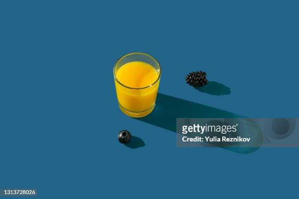glass of orange juice with blackberry and blueberry on the blue background - orange juice stock pictures, royalty-free photos & images
