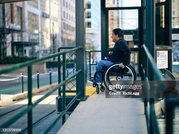 homme handicapé sur une rampe de fauteuil roulant - accessibilité aux personnes handicapées photos et images de collection