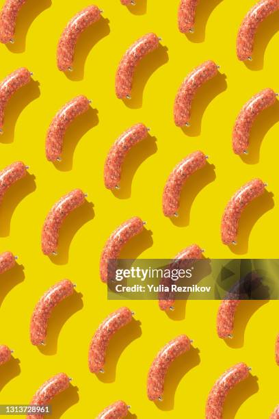 repeated mettwurst on the yellow background- mettwurst is a flavored german sausage made from raw minced pork preserved by curing and smoking. - breakfast sausage stock pictures, royalty-free photos & images